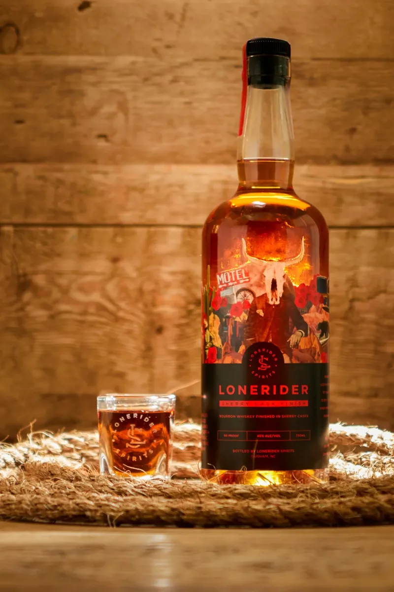 A bottle of Lonerider Sherry Cask with a glass, on a coiled rope.